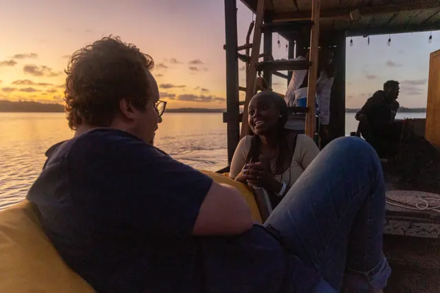 Festival guests in conversation aboard a dhow at golden hour