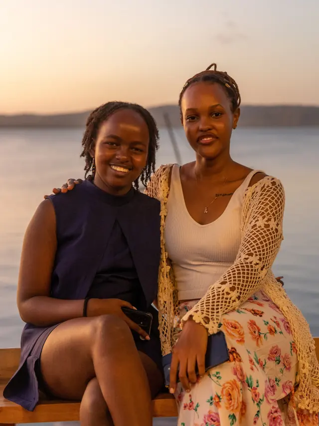 Two festival guests seated together beside Kilifi Creek at sunset
